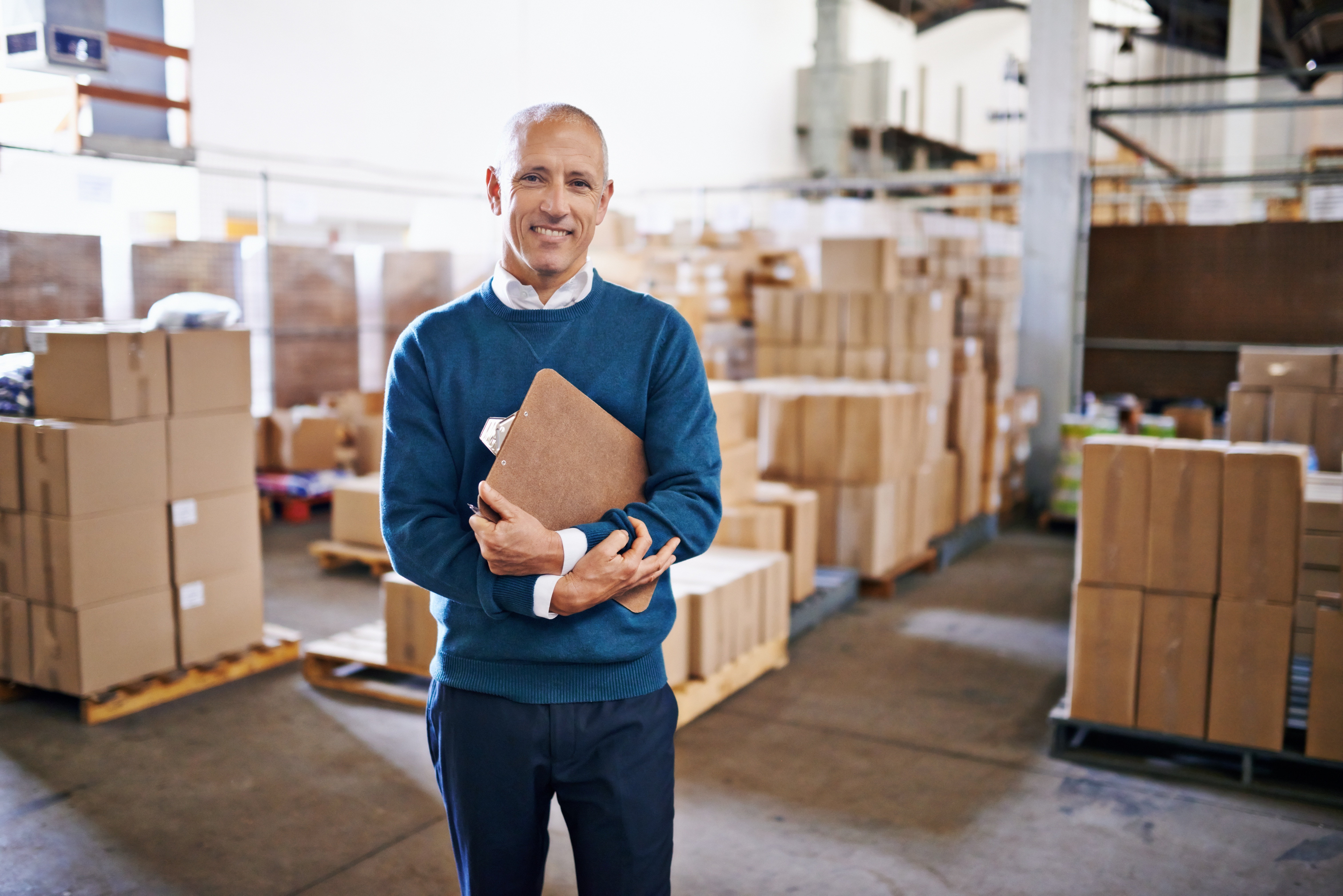 Smiling man standing in warehouse. He's happy because he used WooCommerce SEO will increase leads and his business is growing.